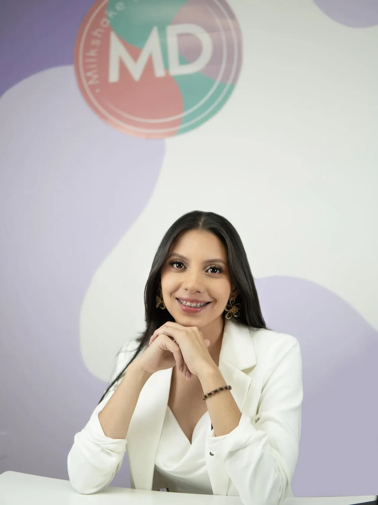Retrato en el estudio de Milkshake Design, frente al logo MD de la pared lila