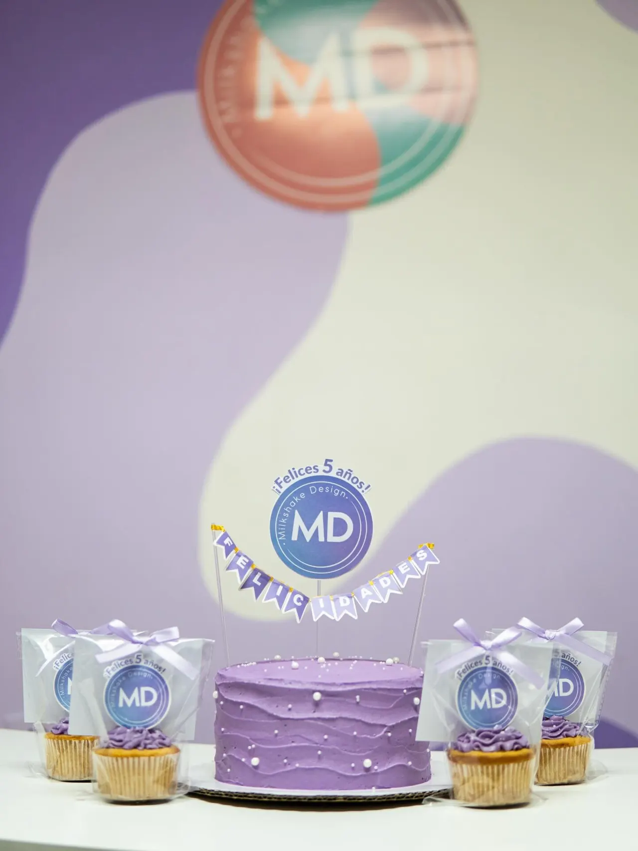 Pastel lila y cupcakes con el logo MD para celebrar los cinco años de Milkshake Design